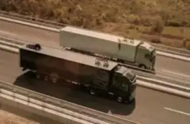 Mujer equilibrista camina por una cuerda sujetada entre dos camiones en movimiento