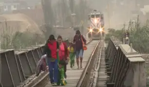 Padres con sus hijos arriesgan su vida para ganar el paso al tren