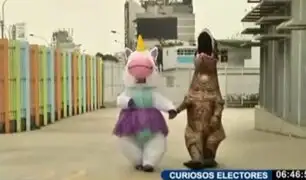 Pareja vestida de unicornio feliz y dinosaurio llegaron de la mano para votar