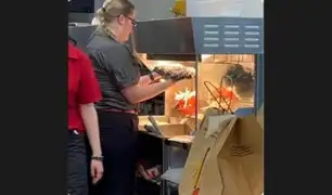 Trabajadora de cadena de comida rápida seca trapo cerca de calentador de papas fritas